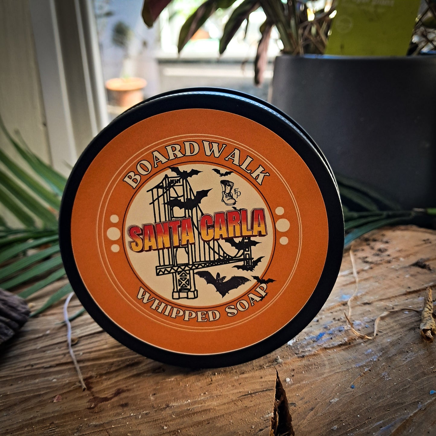 Boardwalk Whipped Soap on wooden surface with plants in the background.
