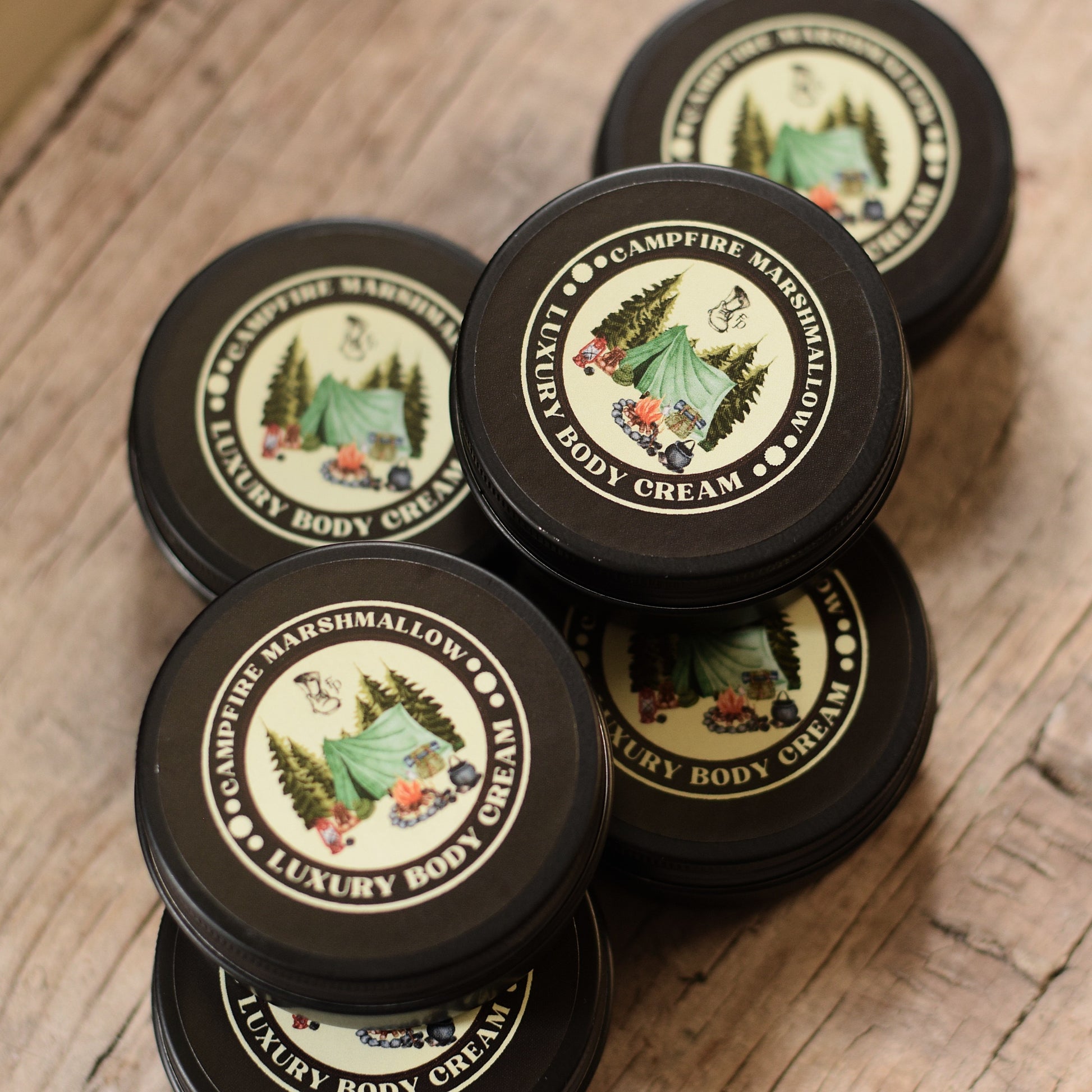 Multiple jars of Campfire Marshmallow Luxury Body Cream on a wooden surface