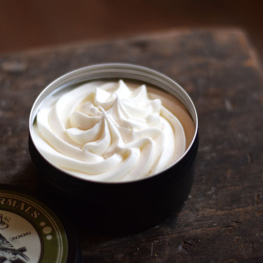 piped body butter in a tin sat on a wooden surface
