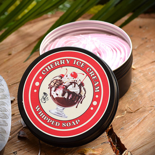 Cherry ice cream whipped soap in a container with a decorative label on a wooden surface.