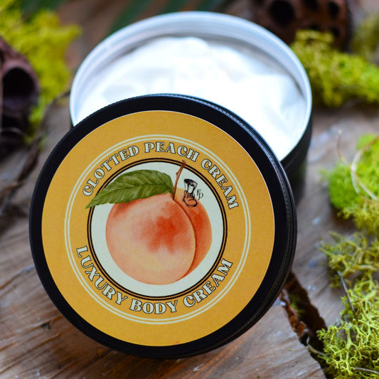 Jar of Clothed Peach Cream Luxury Body Cream on a wooden surface with greenery.