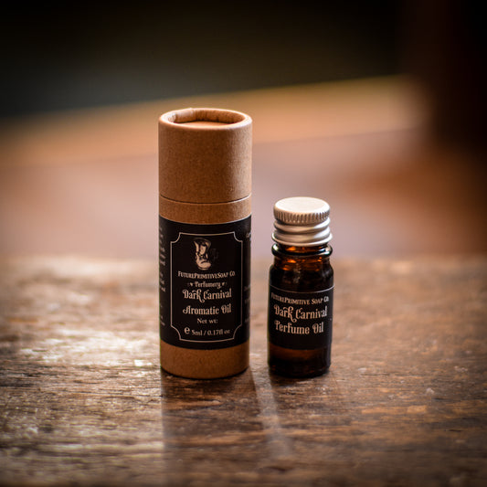 Two bottles of 'Dark Carnival' perfume on a wooden surface with a blurred background