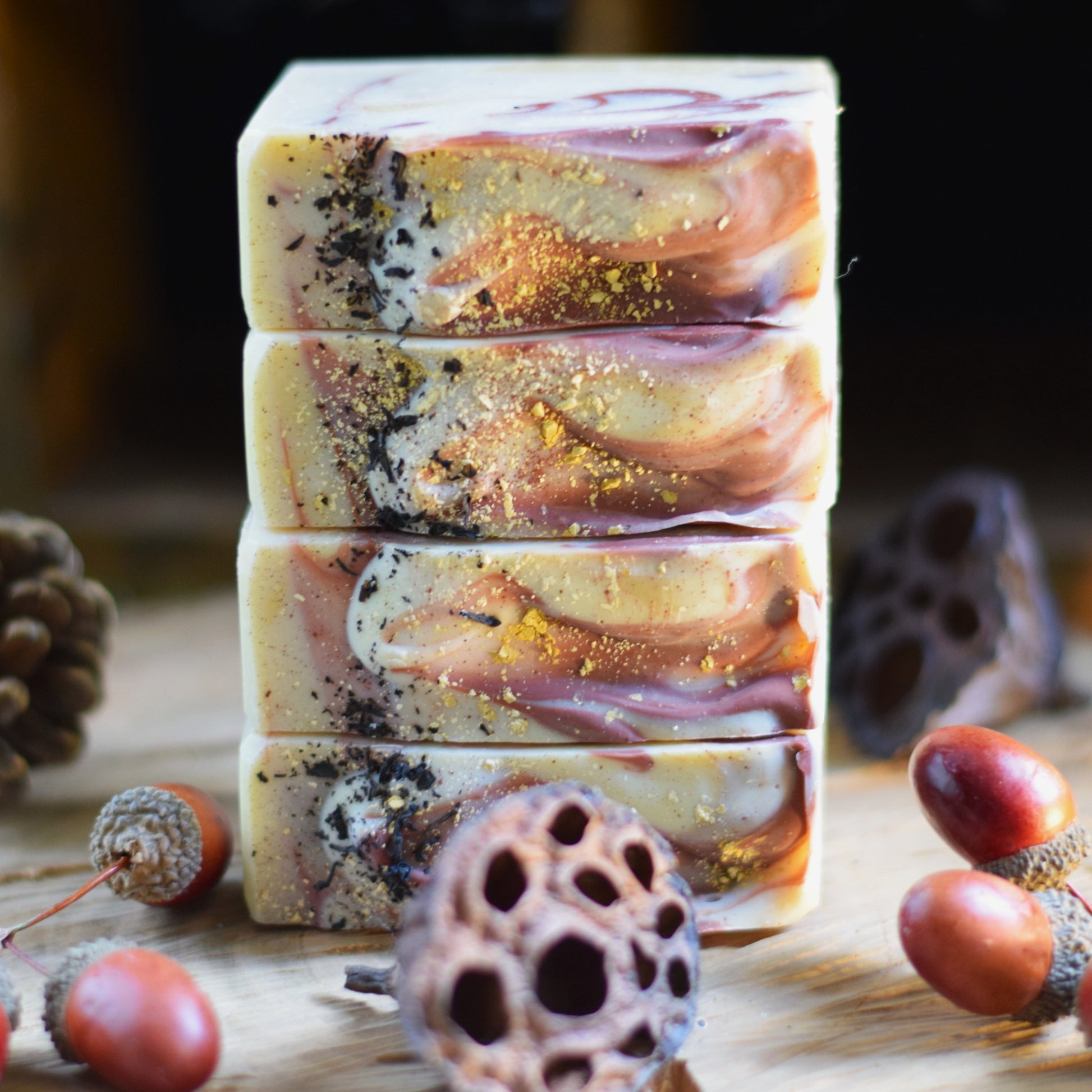 Stack of decorative soap bars with natural elements on a wooden surface