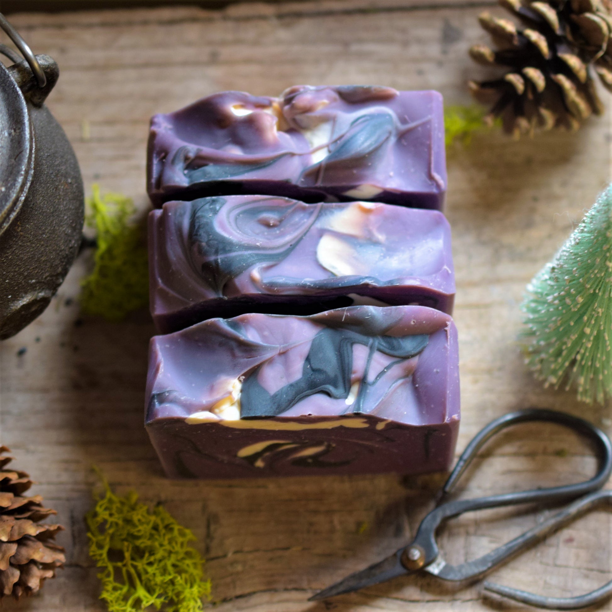 Marbled purple and green soap bar on a wooden surface with natural elements