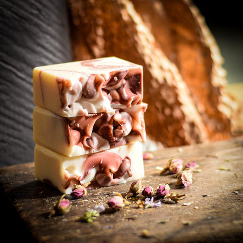 Stack of red and white layered soap bars on a wooden surface with flowers