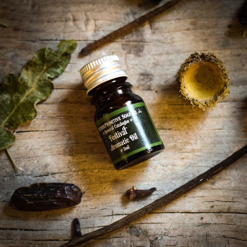 Bottle of Festival Aromatic Oil on a wooden surface with natural elements