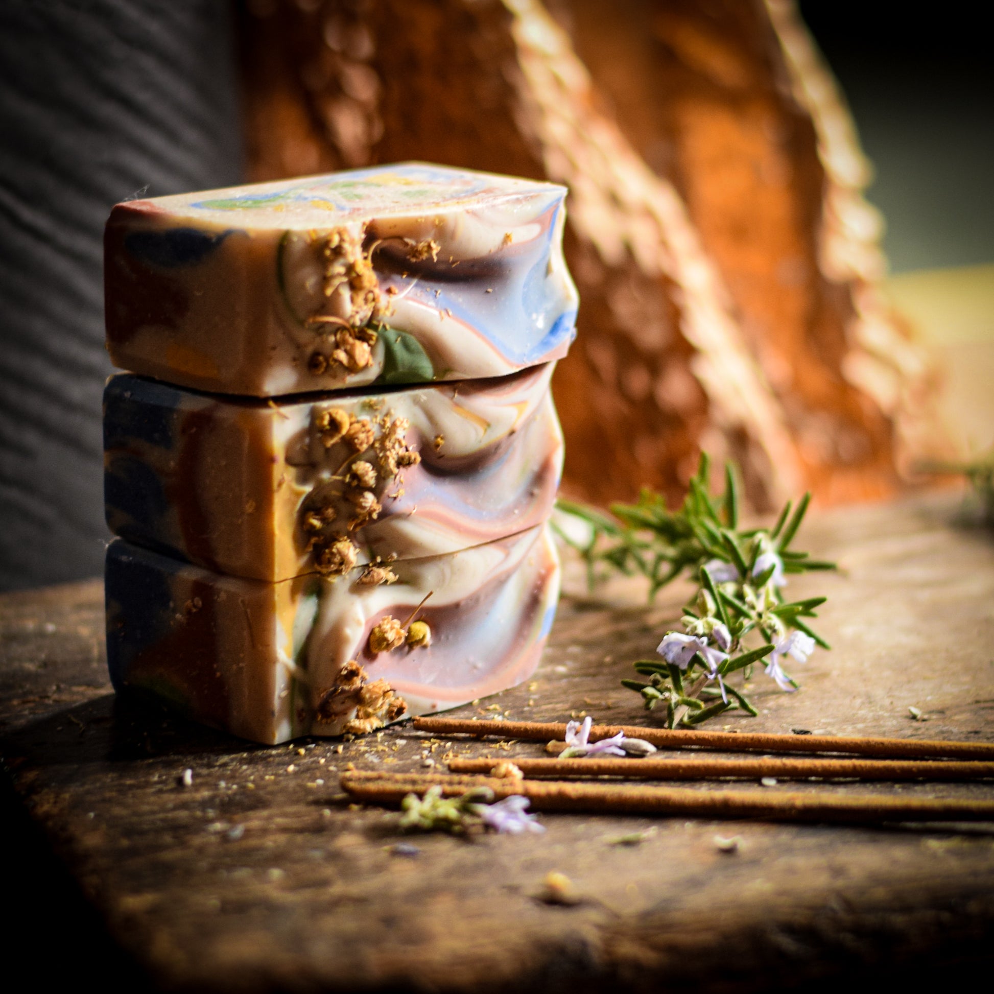 Stack of handmade soap bars with natural elements on a wooden surface