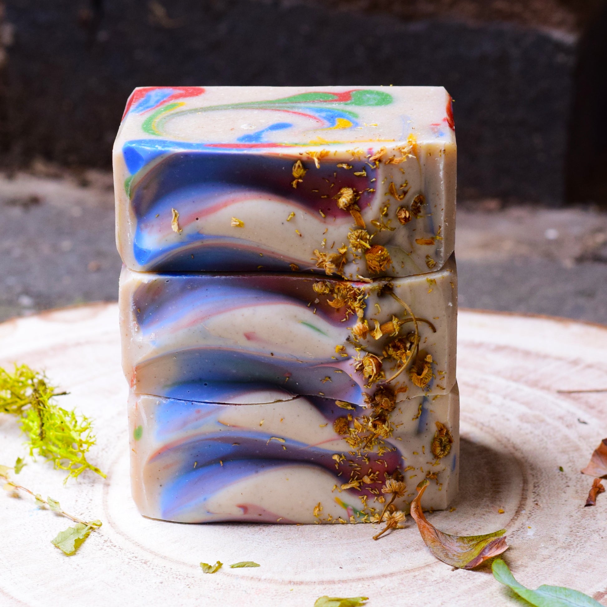 Colorful swirled artisan soap bar with natural elements on a wooden surface