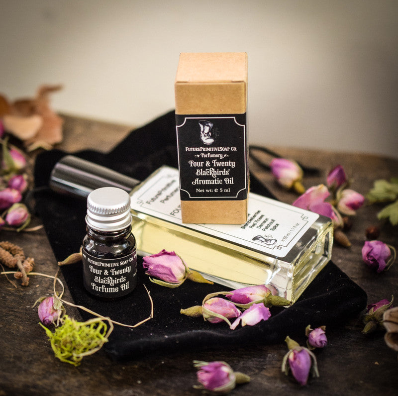 Aromatique Oil packaging with a bottle and box on a dark surface with pink flowers.