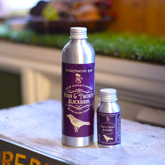 two silver bottles of four & twenty blackbirds hair conditioner on a natural background