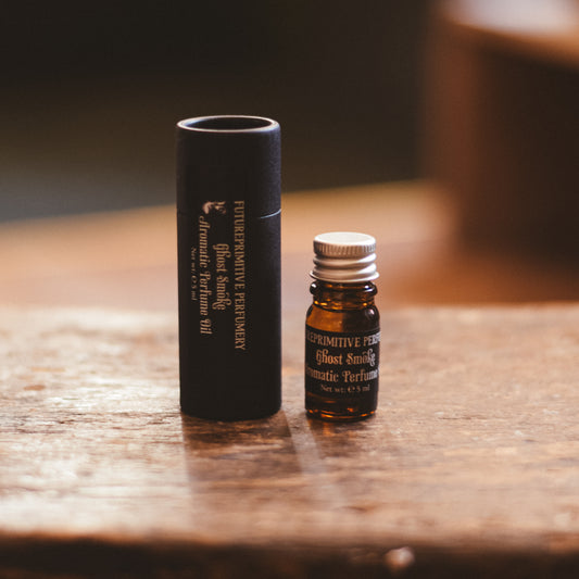 Small brown bottle with a silver cap and black cylindrical container on a wooden surface