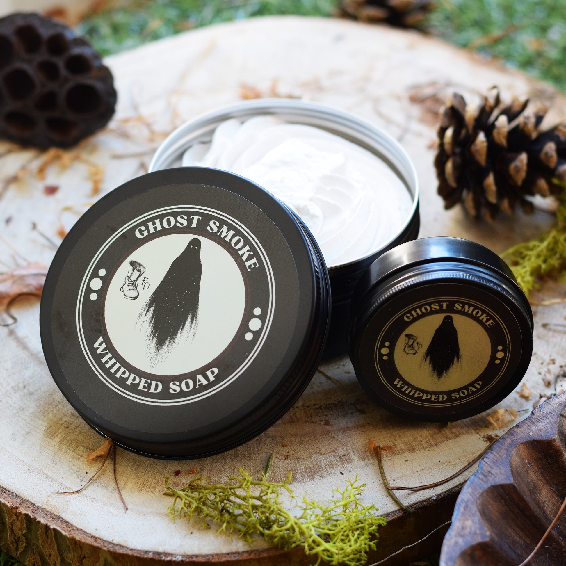 Ghost Smoke whipped soap in a black container on a wooden surface with natural elements.