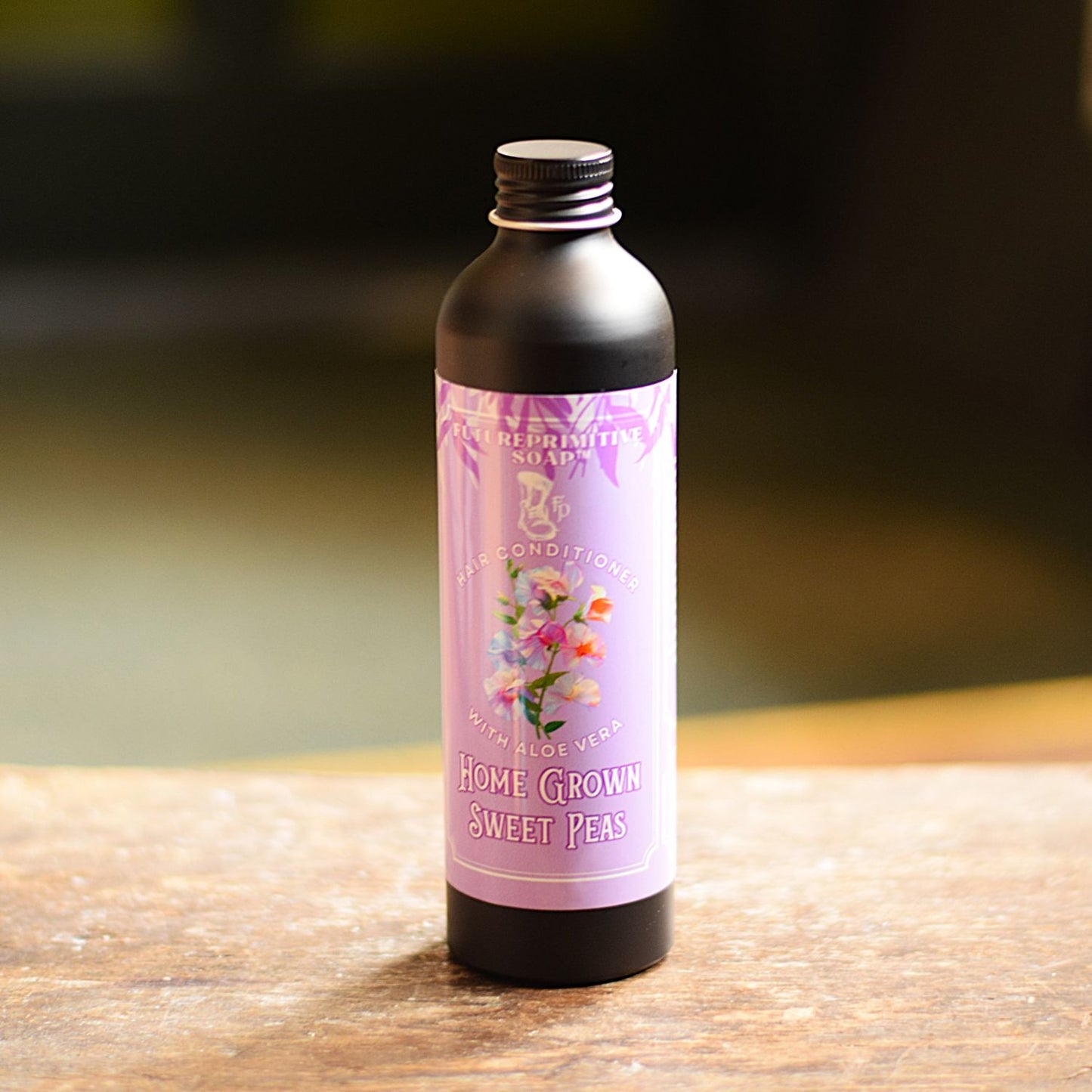 Bottle of 'Home Grown Sweet Peas' soap on a wooden surface with a blurred background
