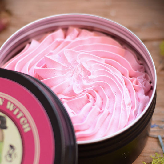 Pink whipped cream soap in a black and pink container with 'Kitchen Witch' branding on a wooden surface.
