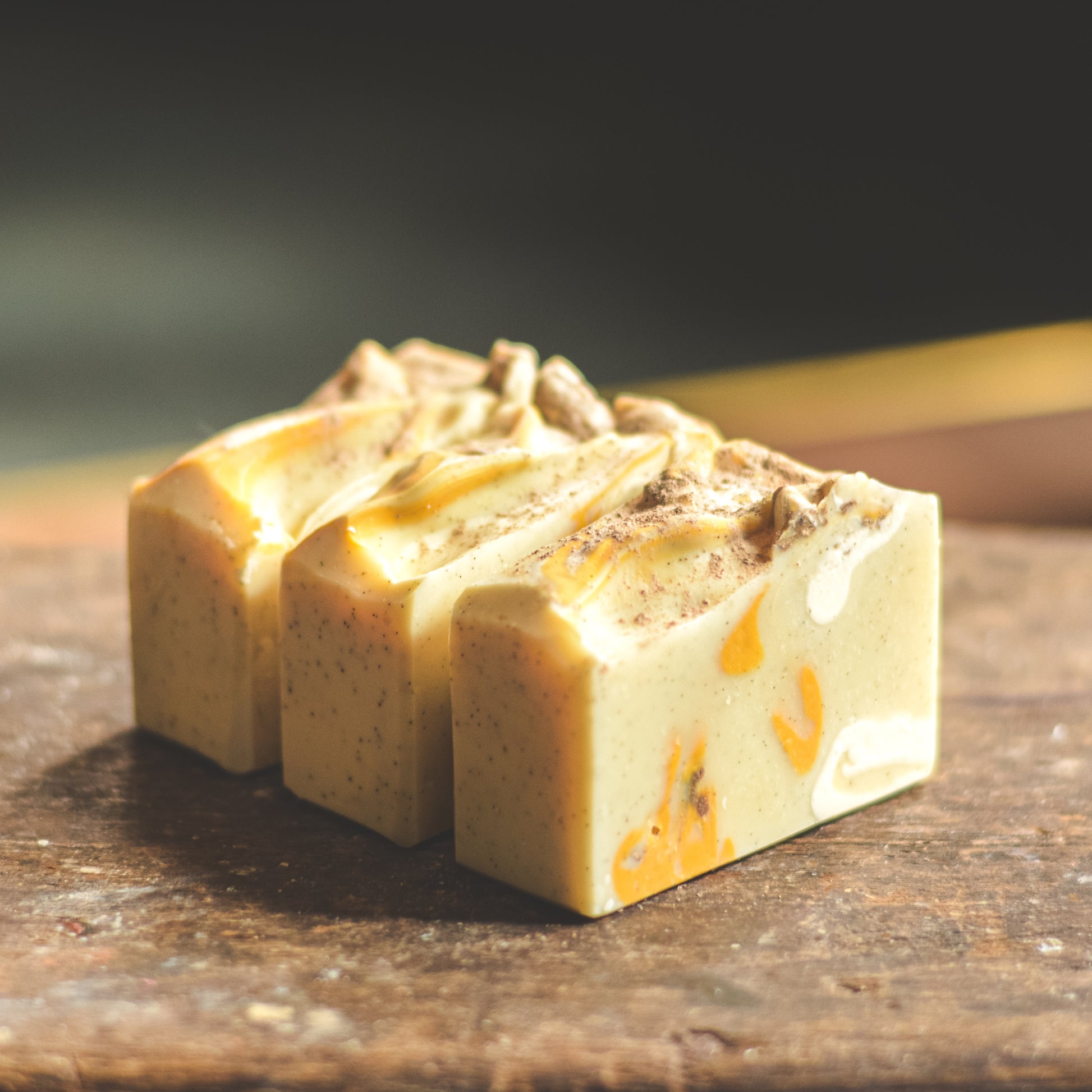 Three square soap bars with a textured surface on a wooden surface