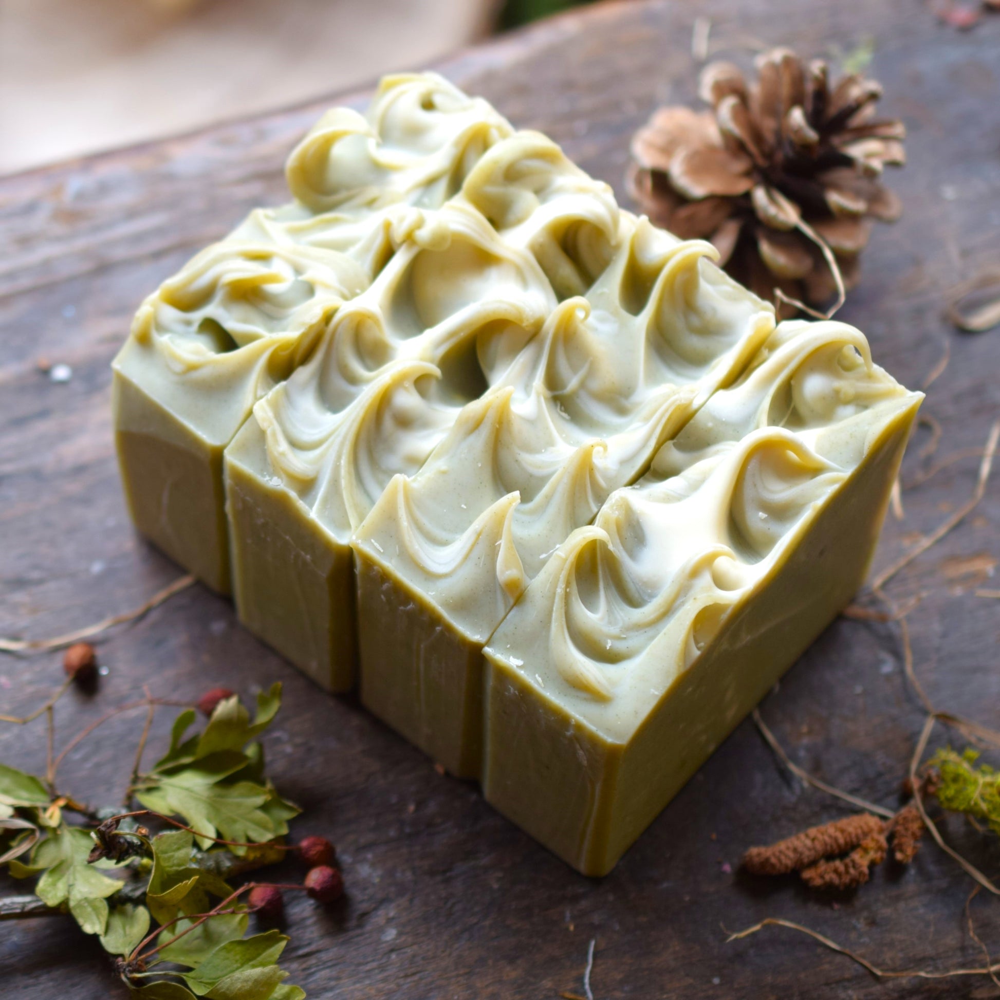 Green soap bar with swirl pattern on a wooden surface with natural elements