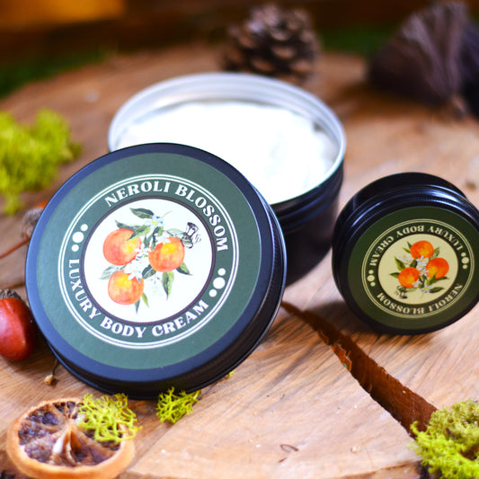 Two containers of Neroli Blossom Luxury Body Cream on a wooden surface with natural elements.