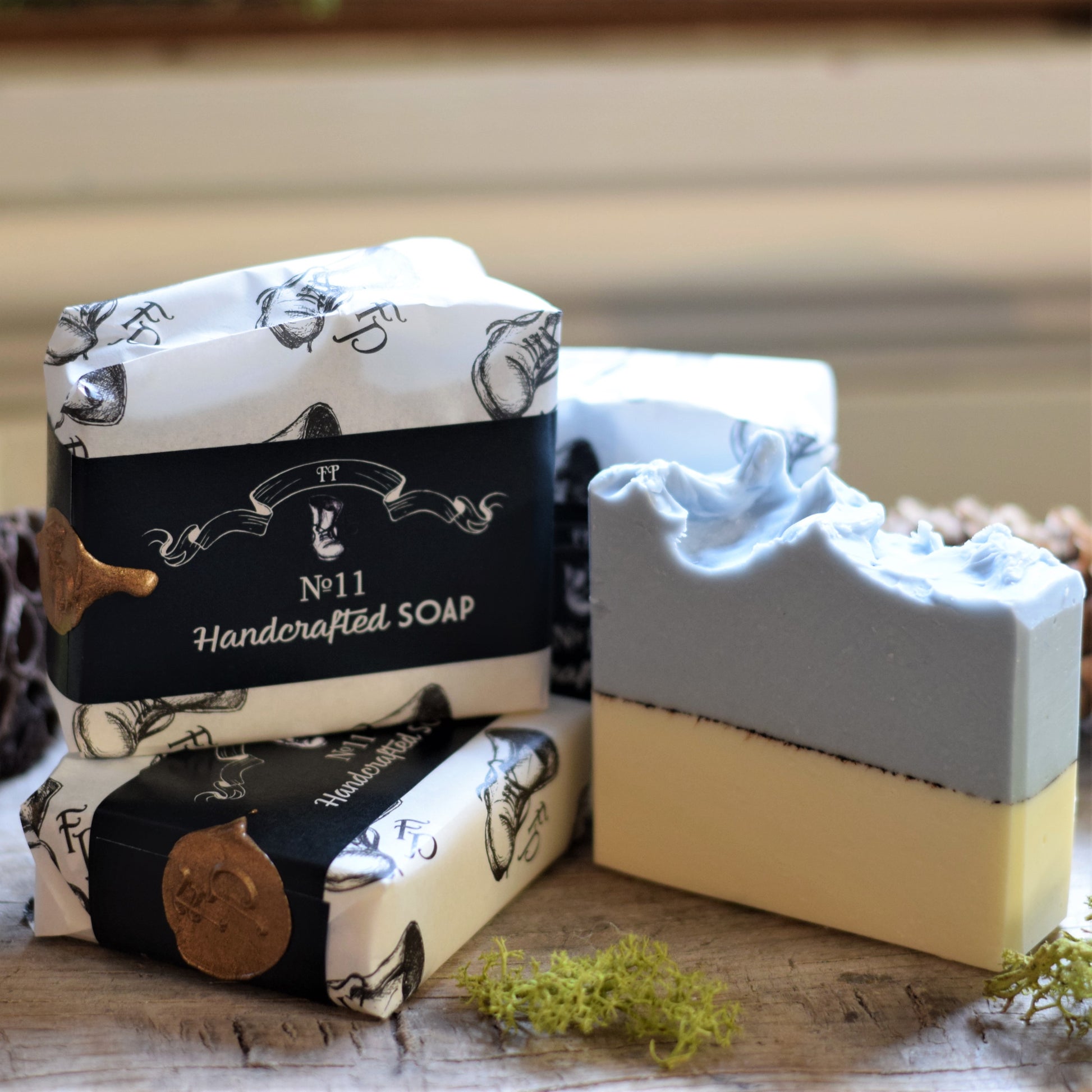 Handmade artisan soap bars with decorative black wrapping with a wax seal on a wooden surface