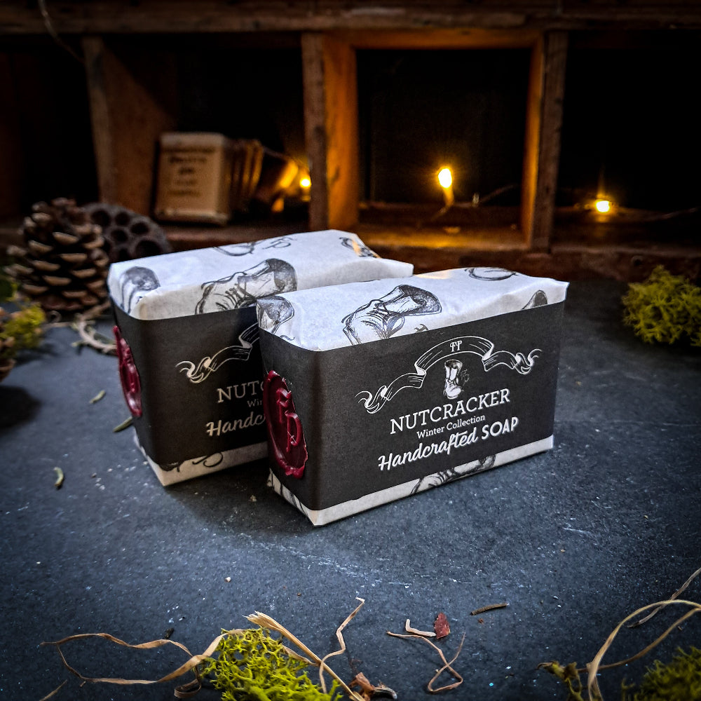 Two boxes of Nutcracker Handcrafted Soap on a dark surface with a fireplace in the background.