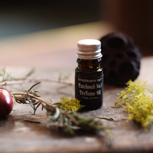 Bottle of Patchouli No.1 Perfume Oil on a wooden surface with herbs and a seed pod