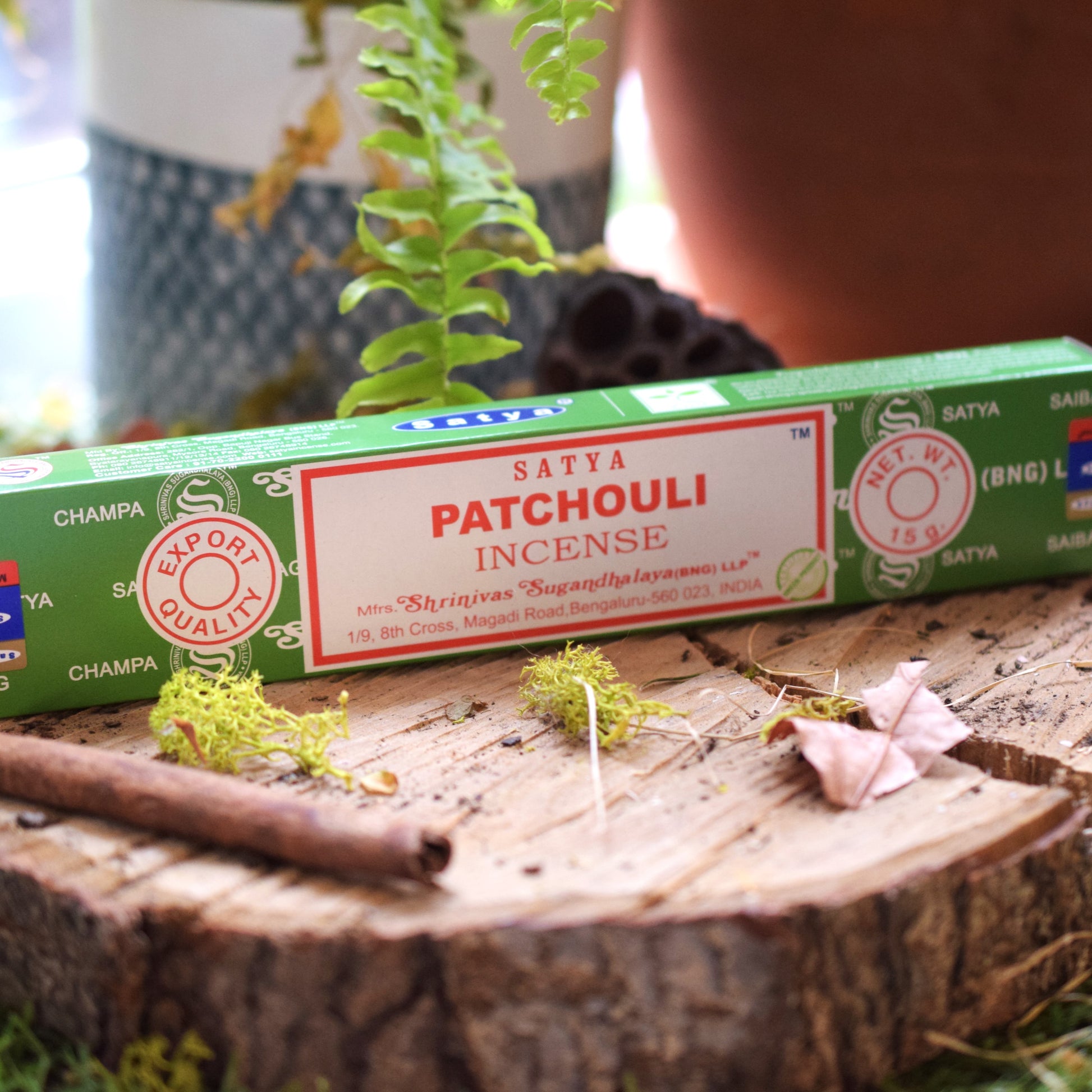 Satya Patchouli incense packaging on a wooden surface with plants in the background