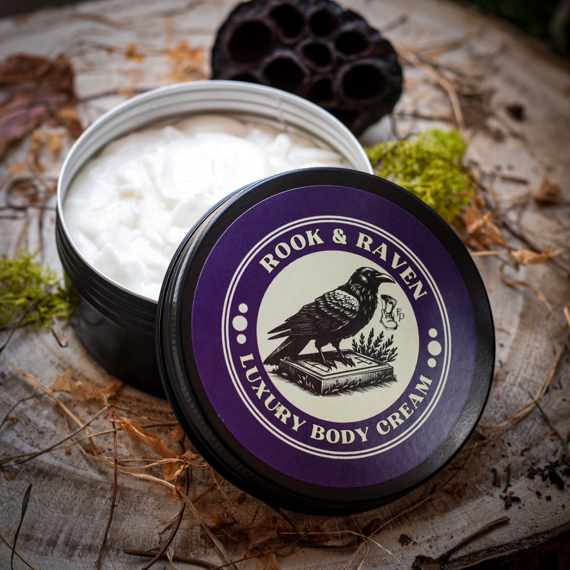 Rook & Raven Luxury Body Cream in a black tin on a wooden table