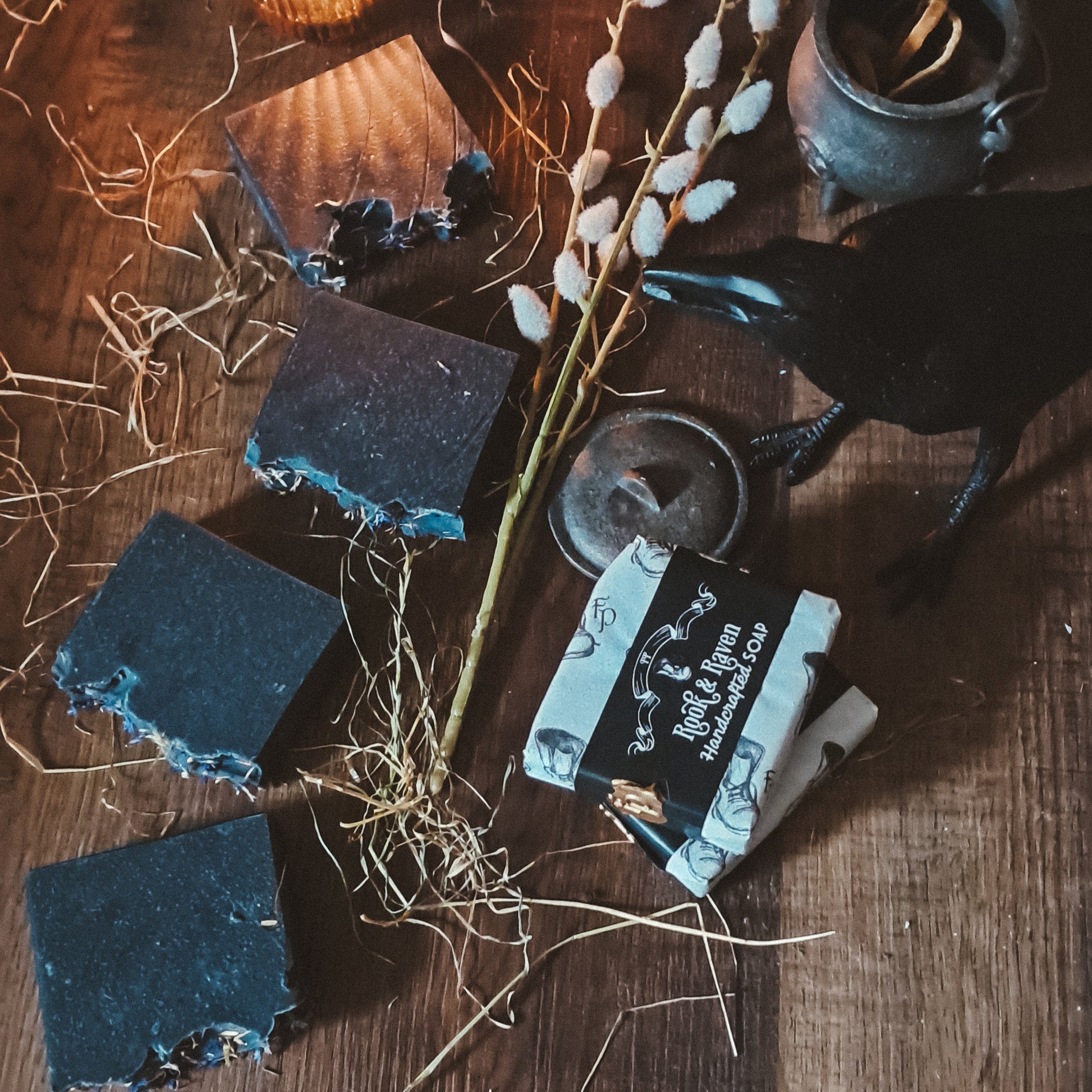 charcoal soap bars on a wooden surface with a candle and willow branch
