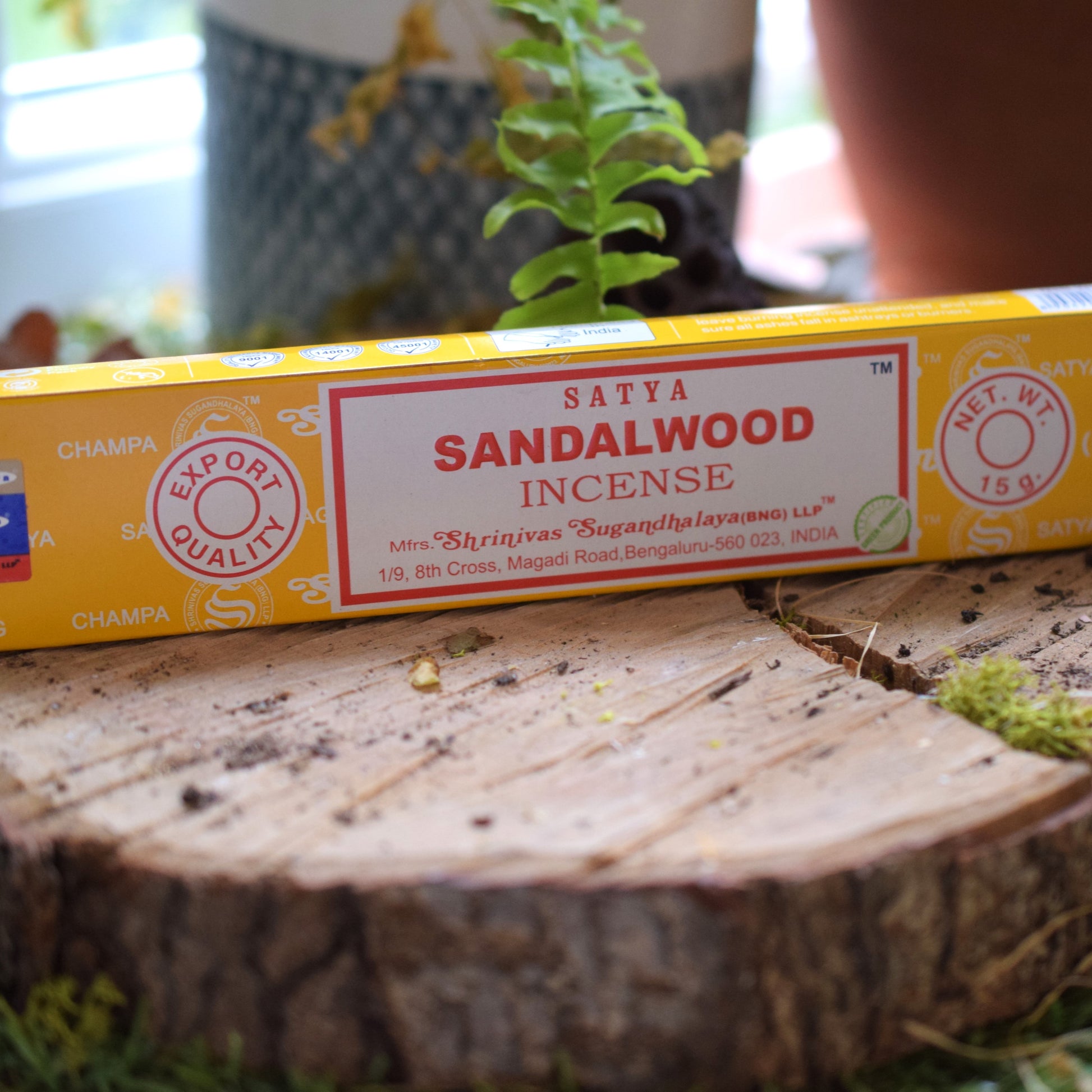 Box of Satya Sandalwood Incense on a wooden surface with plants in the background