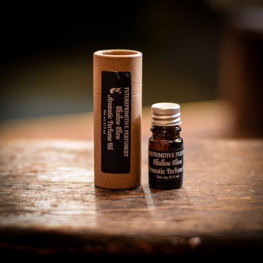 Small shadow show perfume bottle and cardboard tube on a wooden surface with a dark background