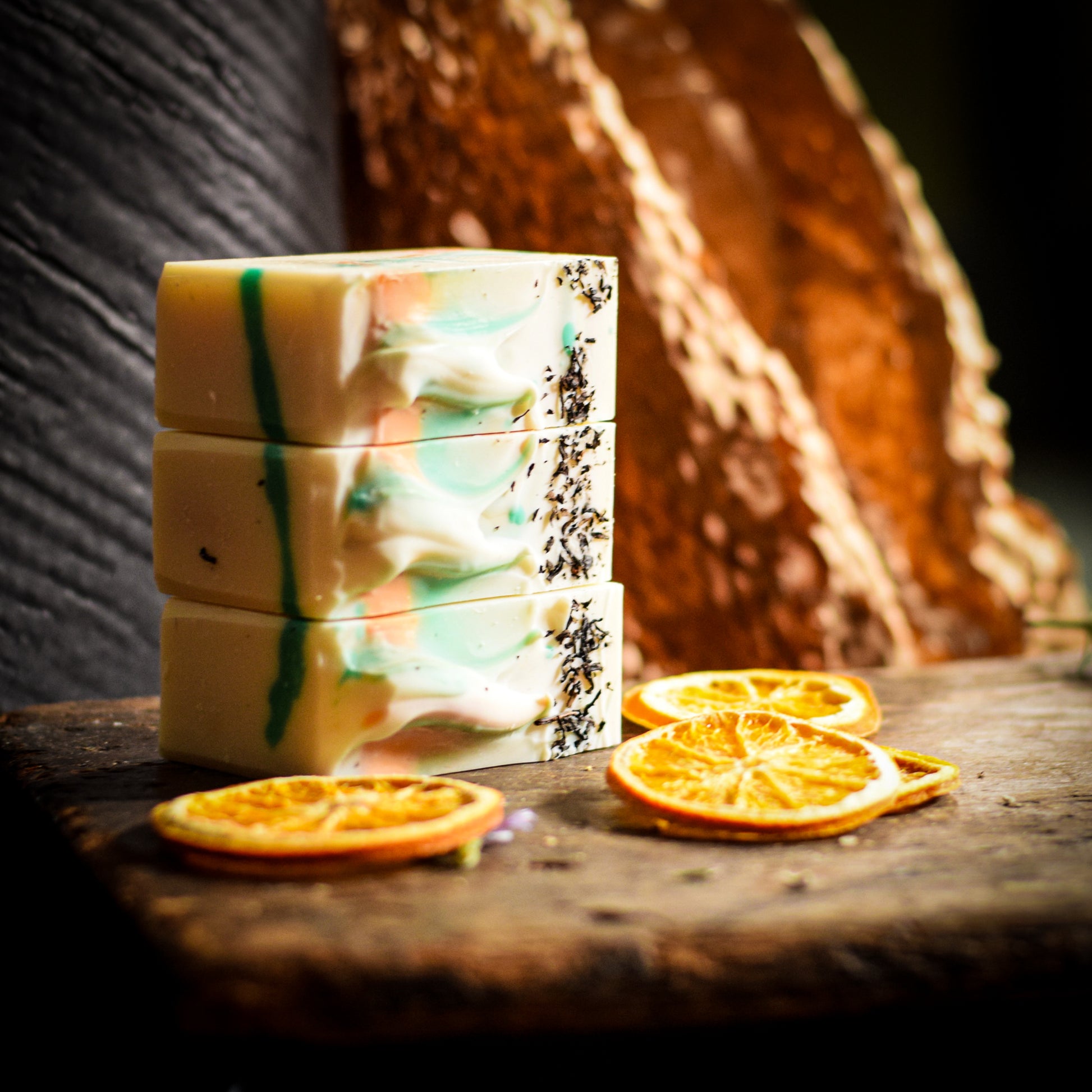 Stack of colorful soap bars with dried orange slices on a wooden surface