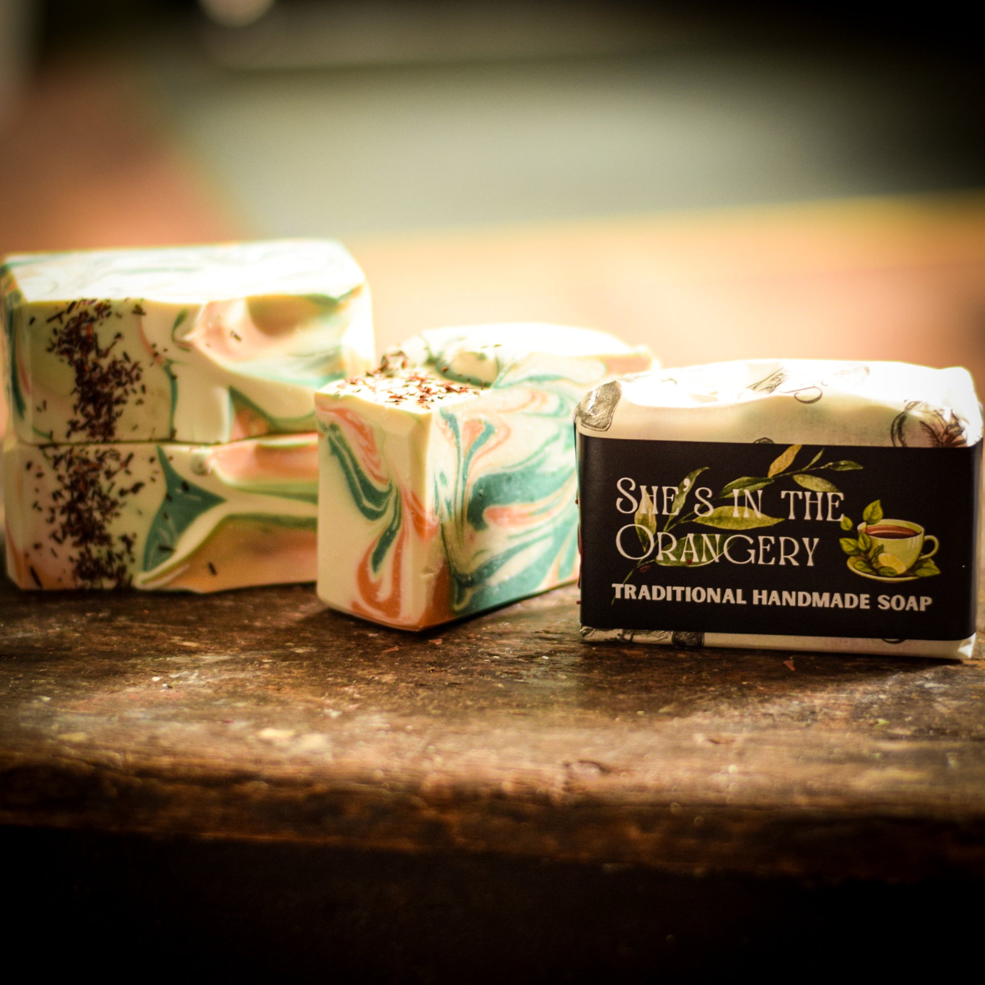 Three bars of soap with marbled designs on a wooden surface, featuring 'She's in the Orangery' branding.