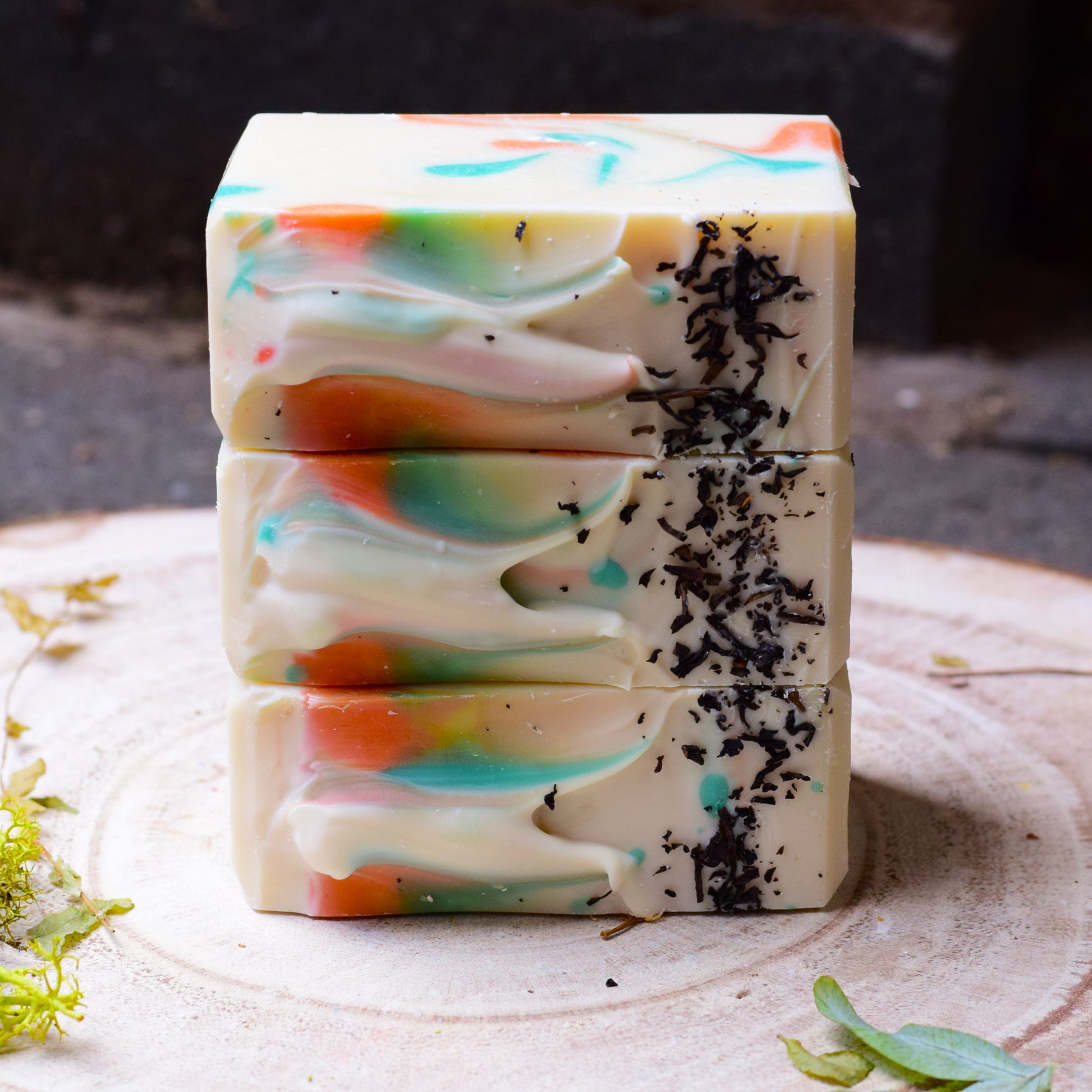 Stack of colorful soap bars with black tea on a wooden surface