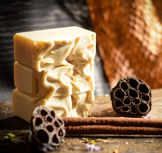 Three stacked soap bars with lotus flower bulbs on a wooden surface