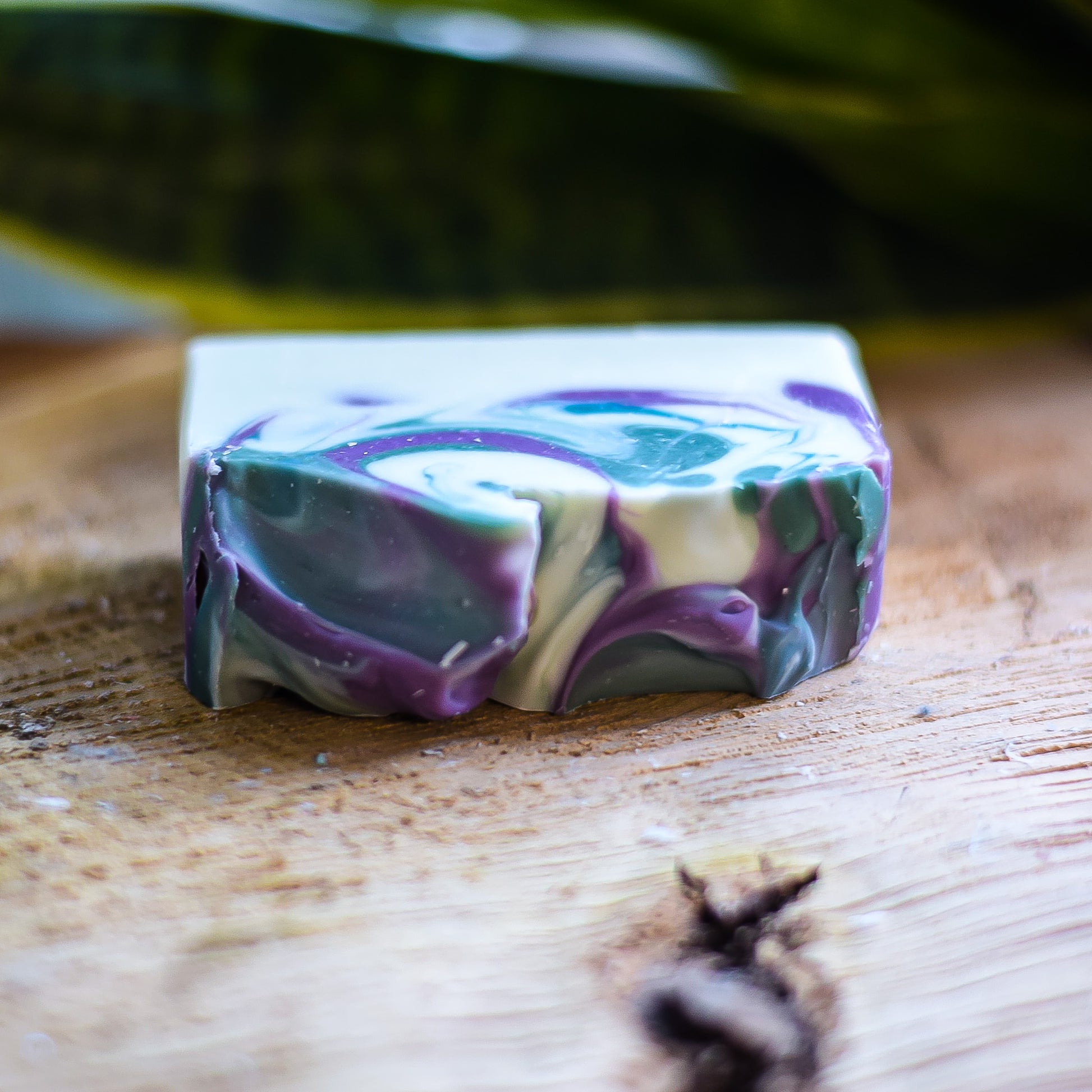 Colorful soap bar with green, purple, and white swirls on a wooden surface.