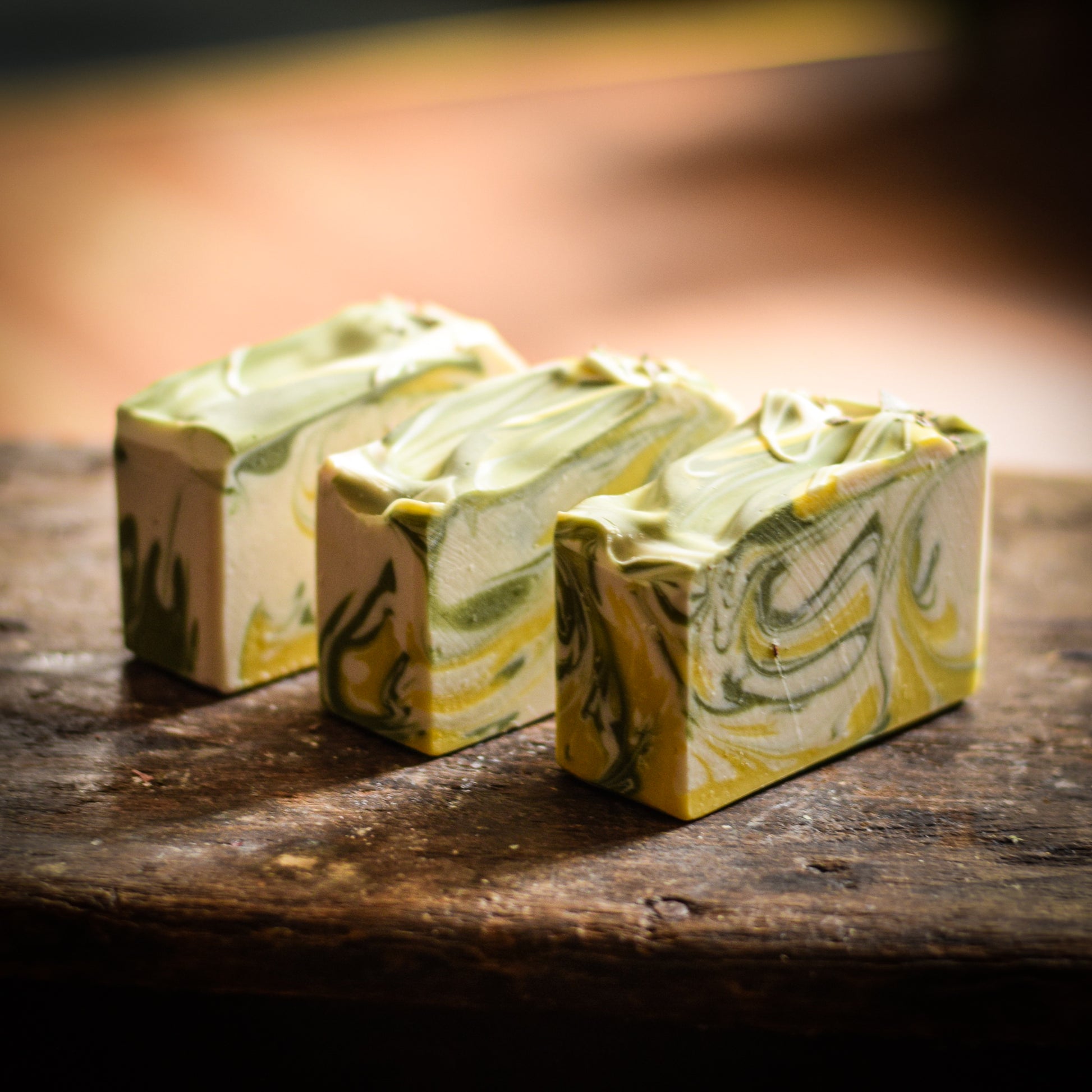 Three bars of green and yellow marbled soap on a wooden surface