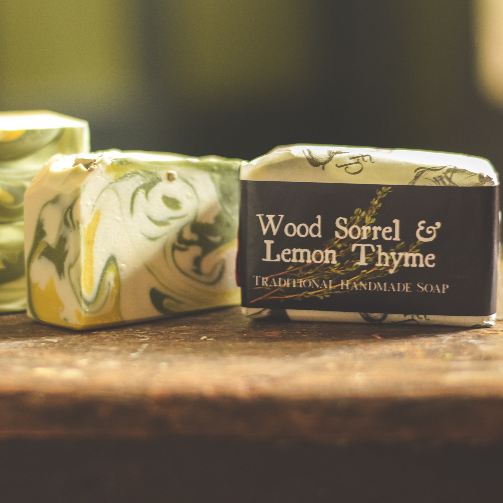 Two bars of soap with decorative wrapping on a wooden surface