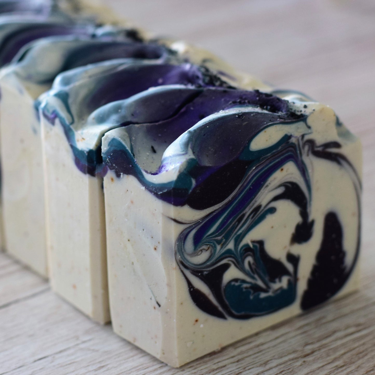 Marbled soap bars with blue and black swirls on a wooden surface