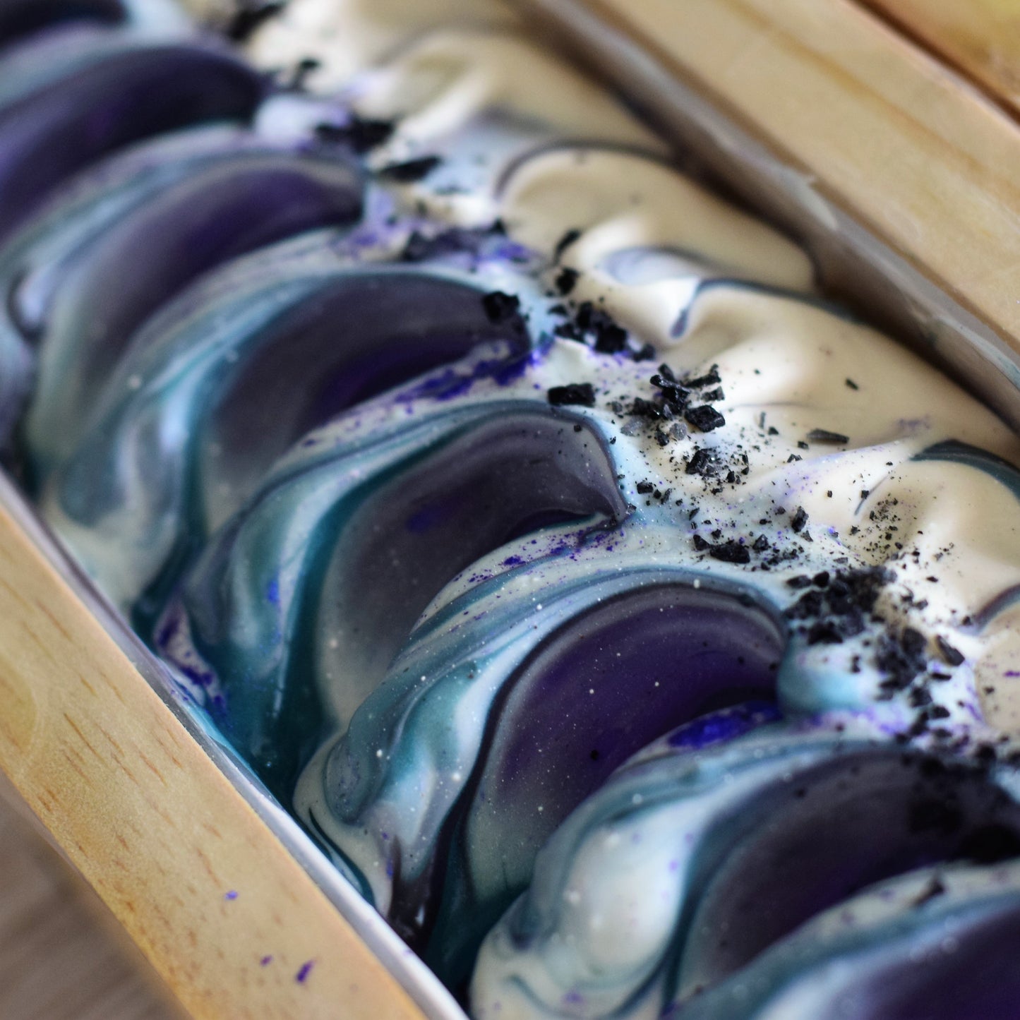 Marbled soap bars with purple and white swirls in a wooden tray