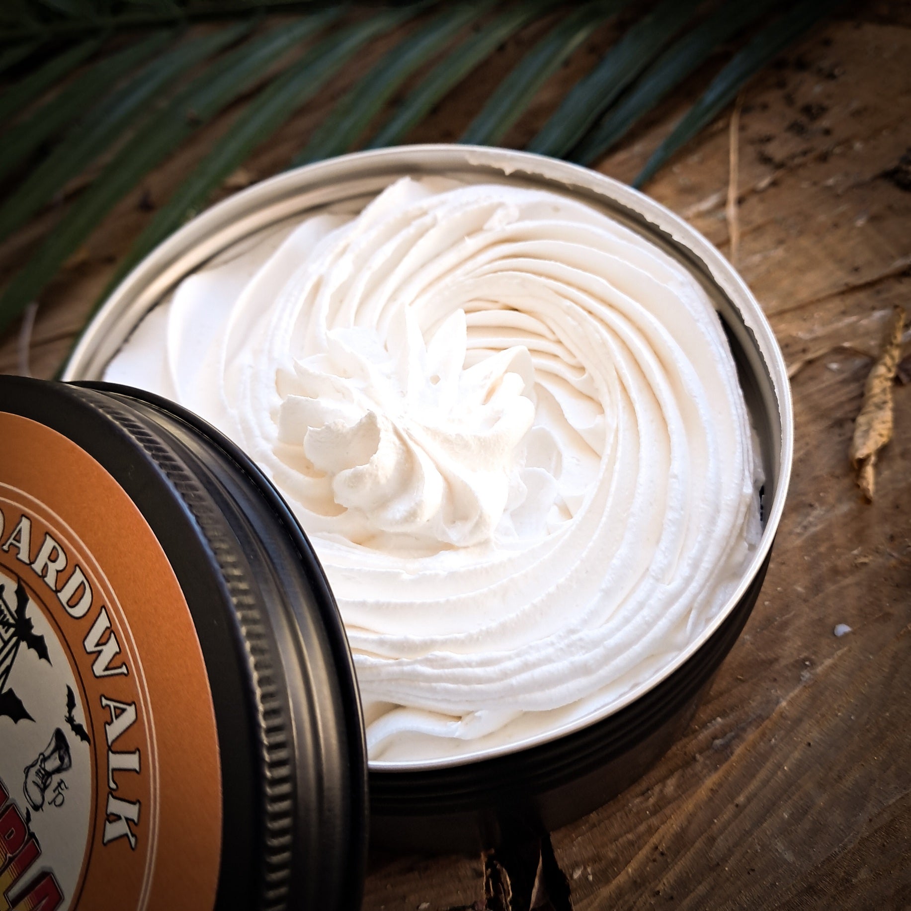 Open jar of shaving cream with a decorative lid on a wooden surface