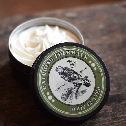 Body butter container with a label featuring a bird illustration on a wooden surface