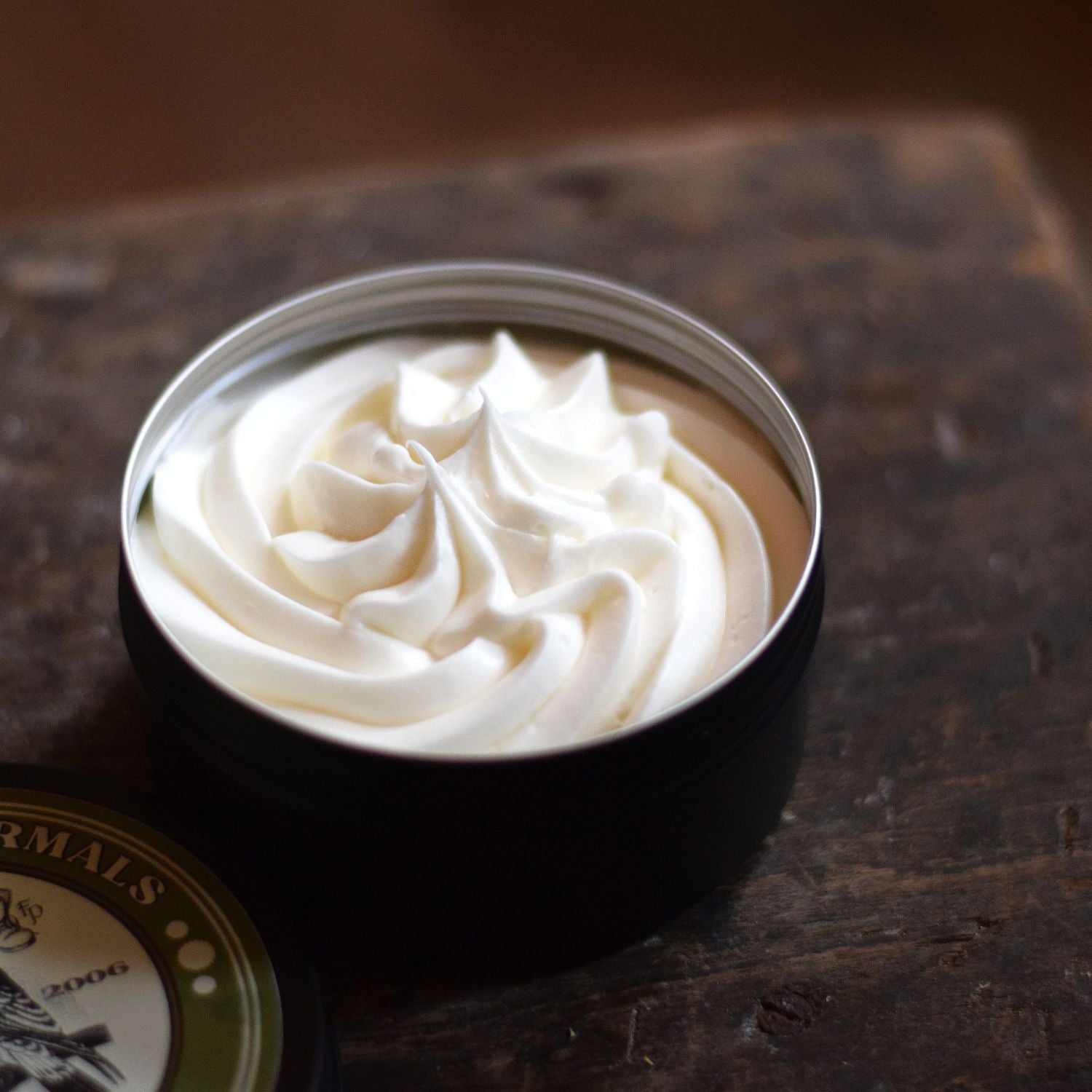 piped body butter in a tin sat on a wooden surface