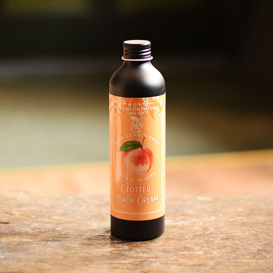 Bottle of Clotted Peach Cream conditioner on a wooden surface with a blurred background