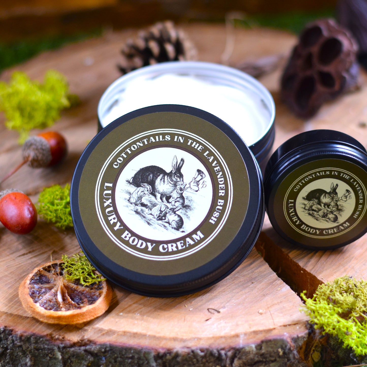 Two containers of 'Cottontails in the Lavender Bush' Luxury Body Cream on a wooden surface with natural elements.