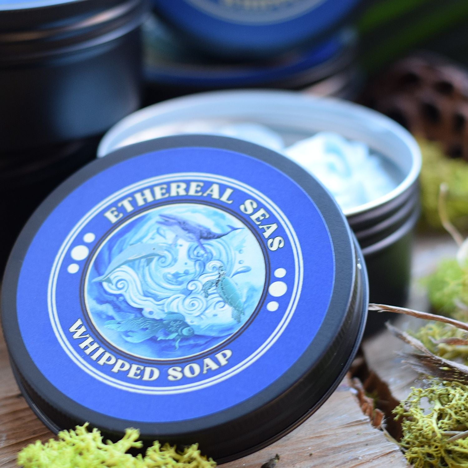 Ethereal Seas whipped soap container with blue label on a wooden surface with greenery.