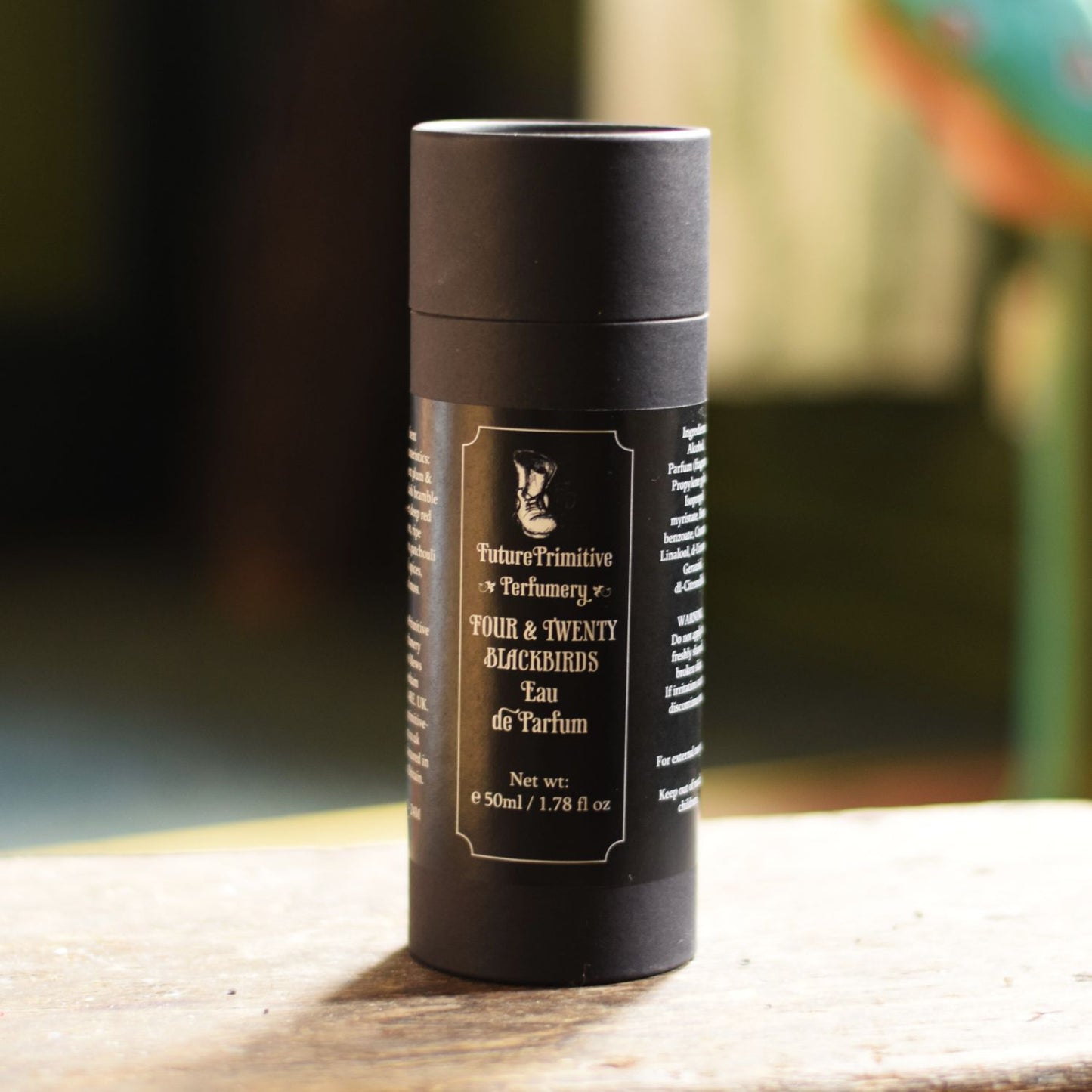 Black cylindrical perfume bottle with text on a wooden surface