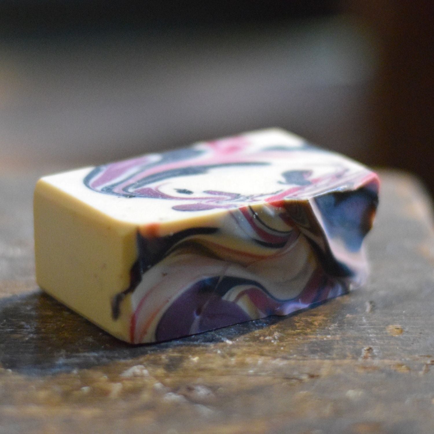 soap bar with dark red, plum and white swirls on a wooden surface