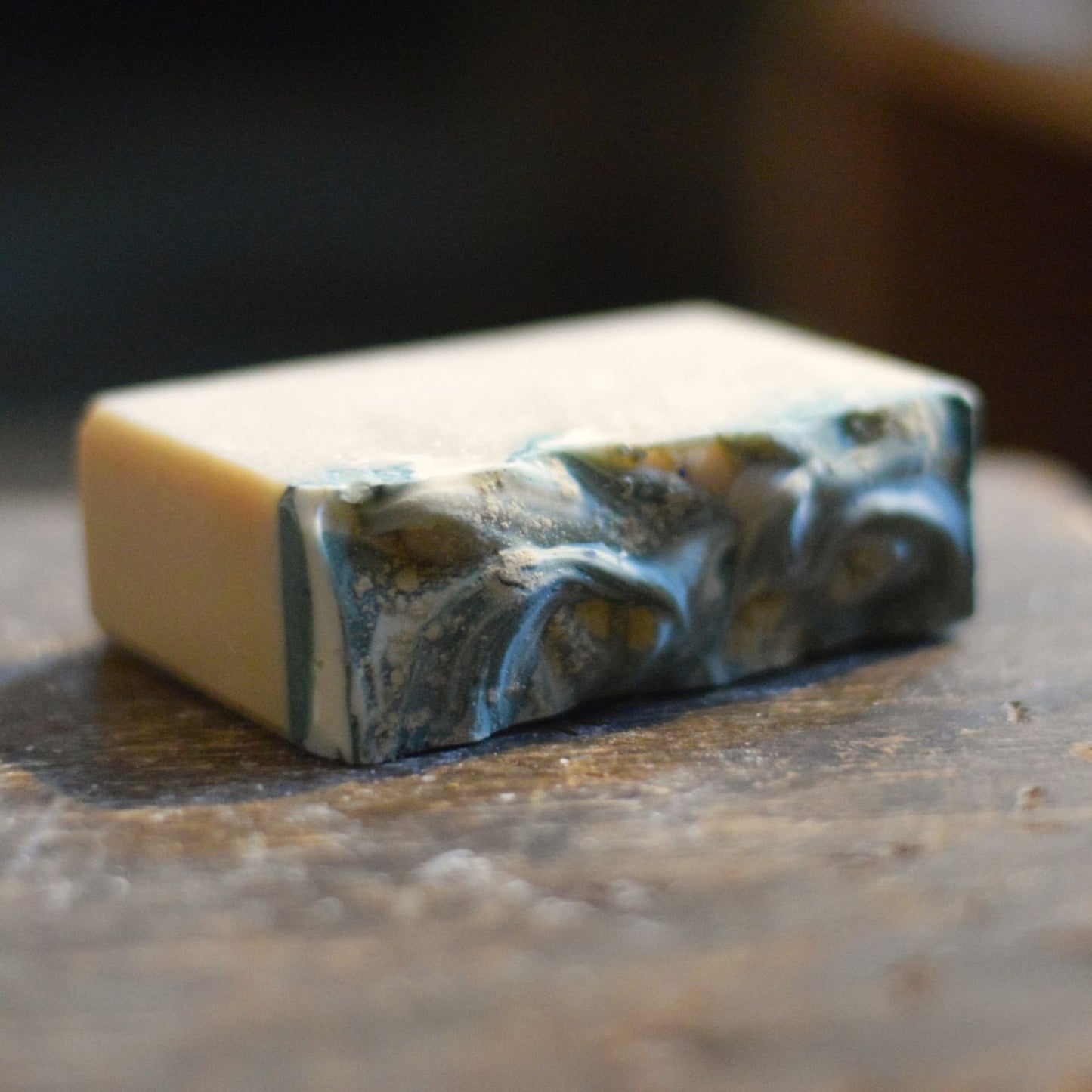 frosted sea glass soap with swirls on top in teal and white on a wooden surface