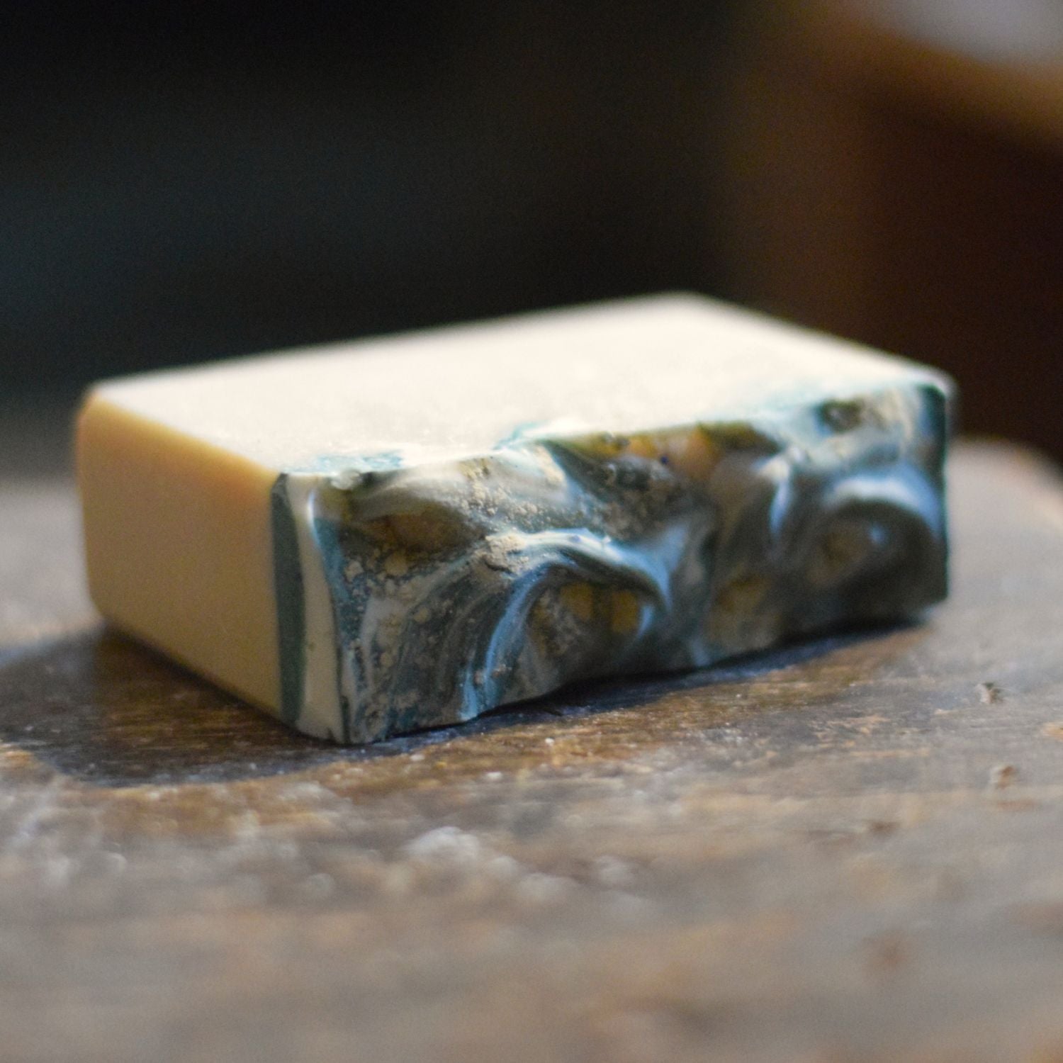 frosted sea glass soap with swirls on top in teal and white on a wooden surface