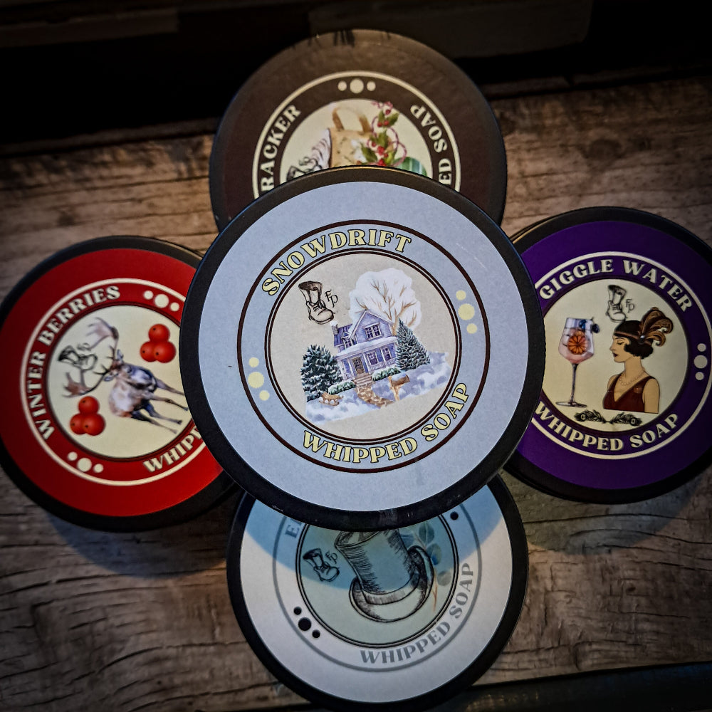 Five different labels of whipped soap on a wooden surface