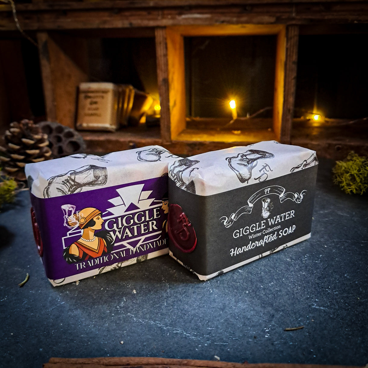Two bars of Giggle Water soap on a dark surface with a rustic background.